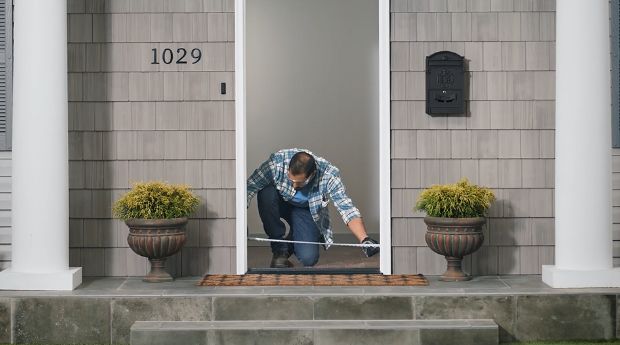 person-measuring-the-width-of-a-rough-opening-on-an-exterior-door