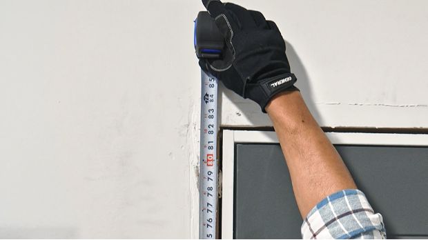 person-measuring-from-the-subfloor-to-the-top-of-the-rough-opening-of-an-exterior-door