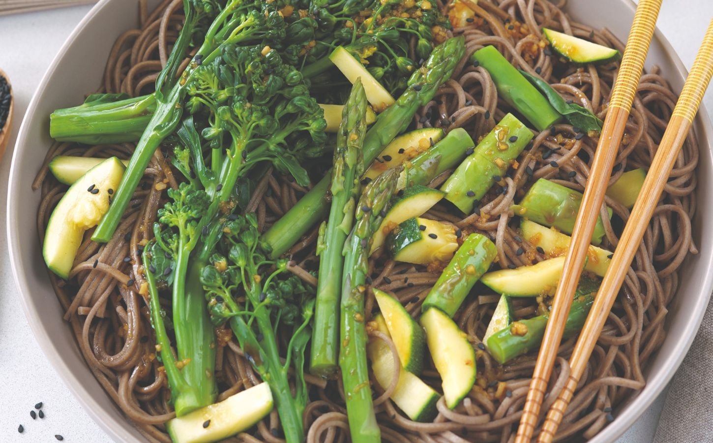 a bowl of vegan sesame ginger cold noodles made with Japanese soba noodles, an Asian-inspired chili, garlic, and ginger dressing, broccolini, and zucchini