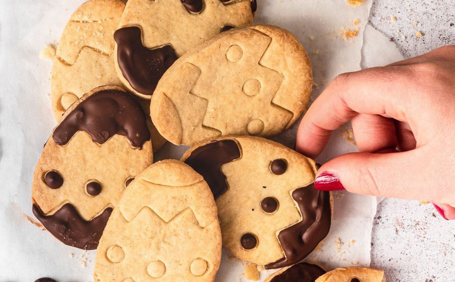 A platter of Easter egg-shaped vegan cookies with chocolate decoration from a recipe